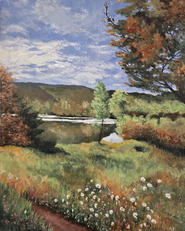 A calm lake below wooded hills turning to autumn, with white daisies through the grass in the foreground
