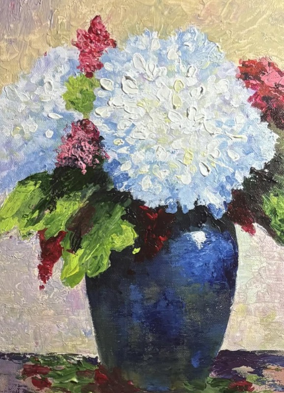 White and pale blue hydrangeas with deep red blooms, arranged in a dark blue vase
