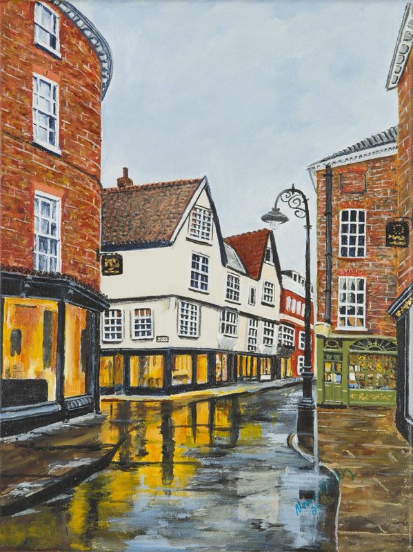 Historic timber and brick town buildings reflected in a rain-soaked street