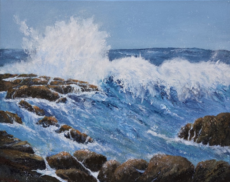 A tall burst of white spray as a wave strikes rocks, under a clear blue sky