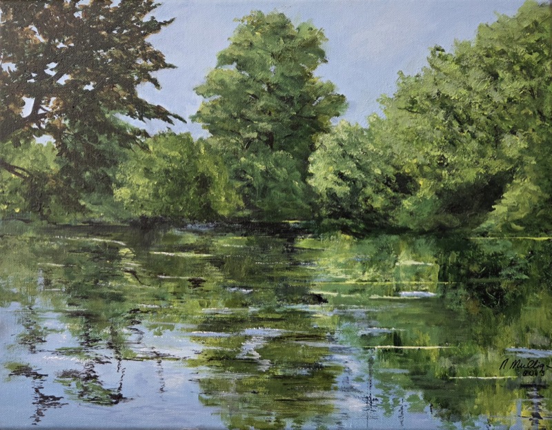 Green summer trees along a riverbank, mirrored in the still water below