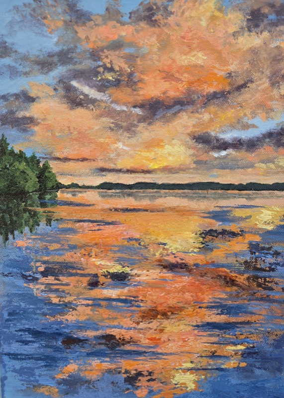 An orange and gold sunset over still water, the burning clouds mirrored across the whole surface
