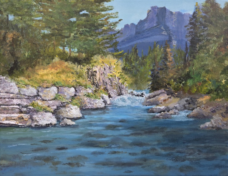 A clear mountain river running between pale boulders and pines, with a bare rock peak rising beyond